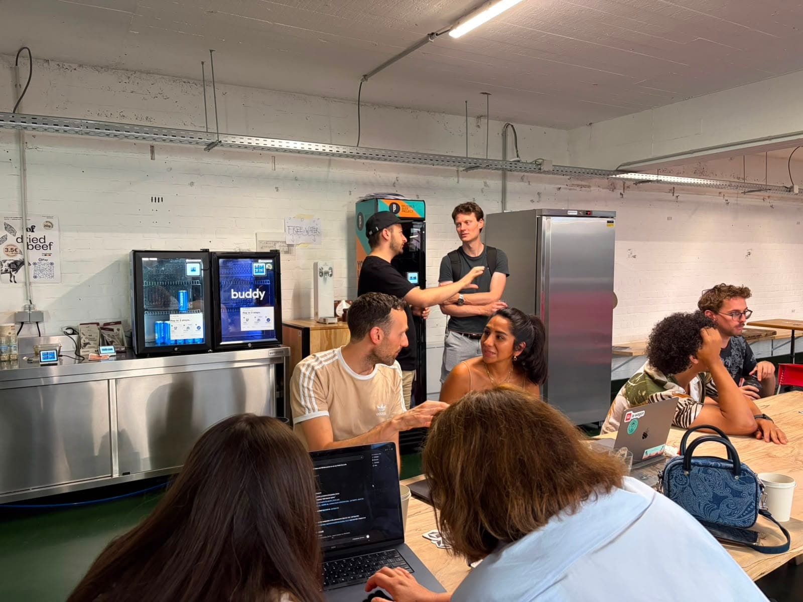 Cursor Meetup Brussels at WAT.BXL, 1 August 2026. Laptops and talk at the long table.
