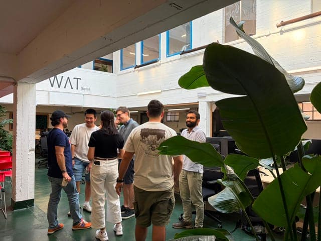 Cursor Meetup Brussels at WAT.BXL, 1 August 2026. Group standing under the WAT (beta) wall mark.